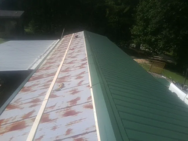 Old rusted panels beside newly installed green metal roofing — Wind Damage Roof Repair by Roofing Brothers in Johns Island