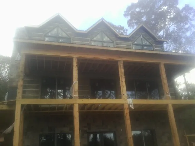 Dormers and porch framing on a large log home under construction — Roof Coating work by our crew in Johns Island