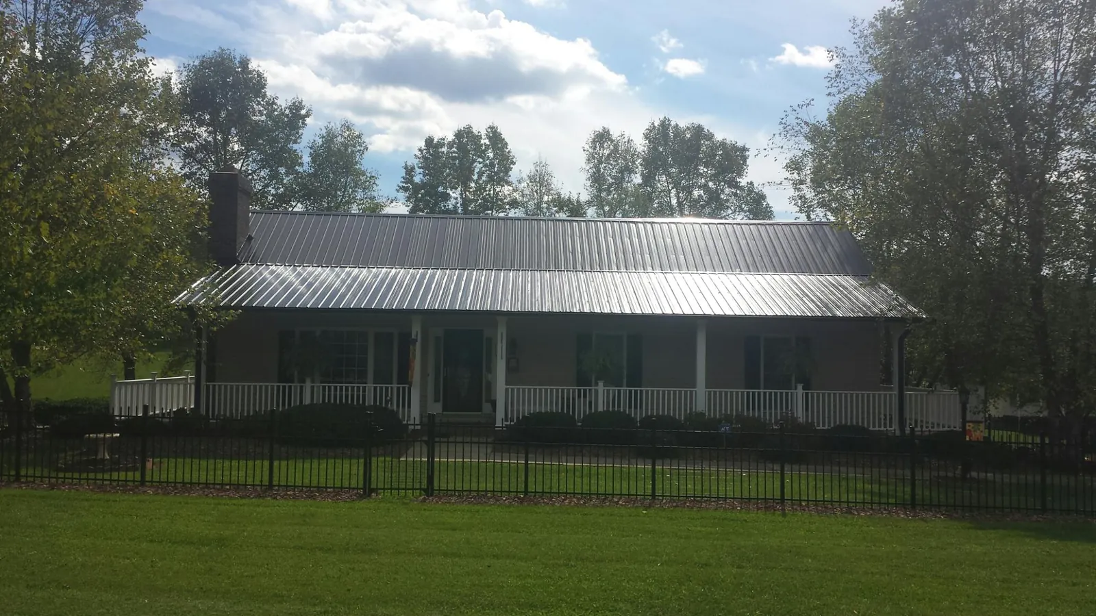 Gray metal roof on a brick ranch with a full width front porch — Gutter Guard Installation work by our crew in Johns Island