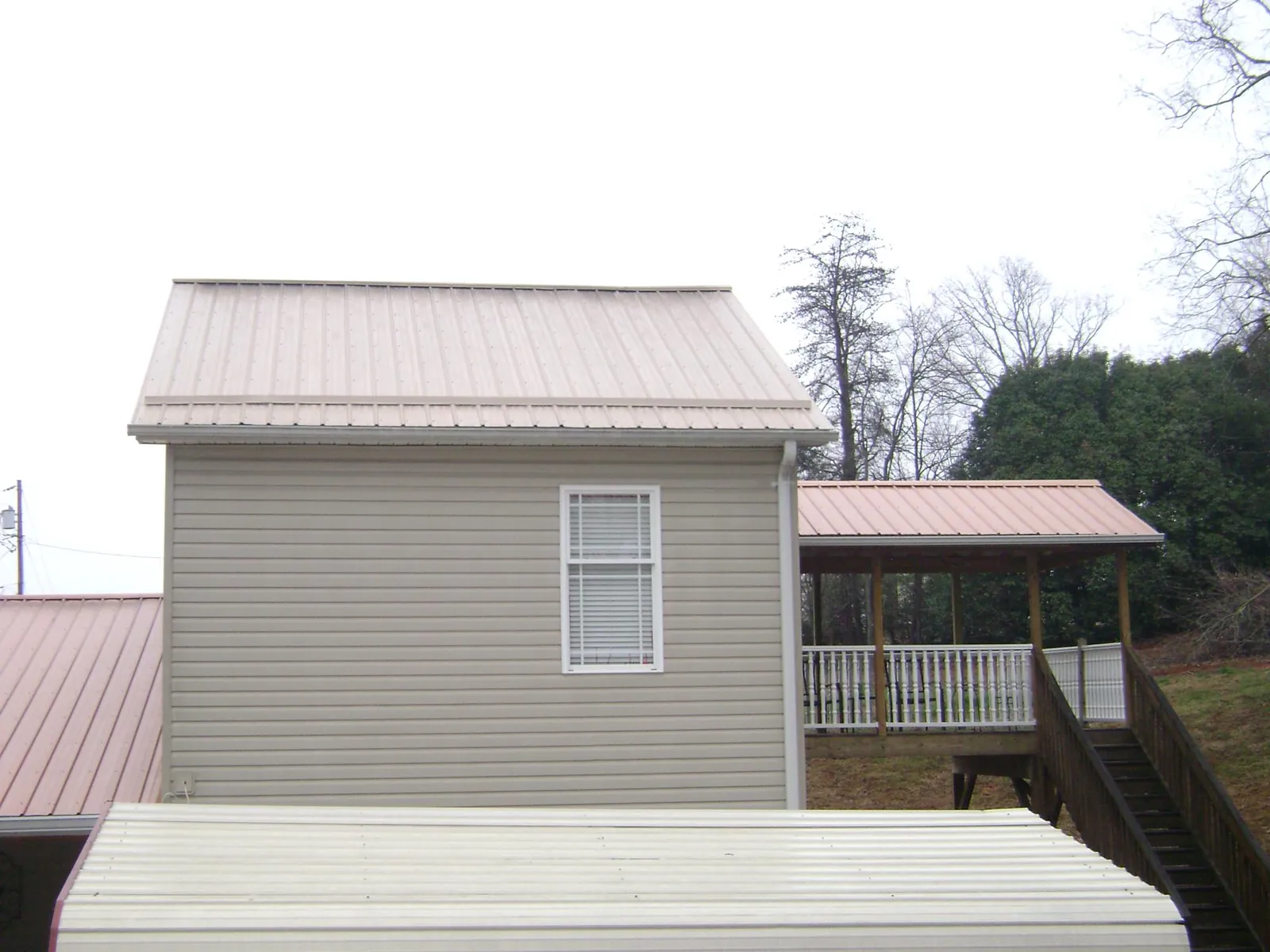 Tan metal roofs on a two story addition and attached porch, from a Roof Replacement job in Johns Island