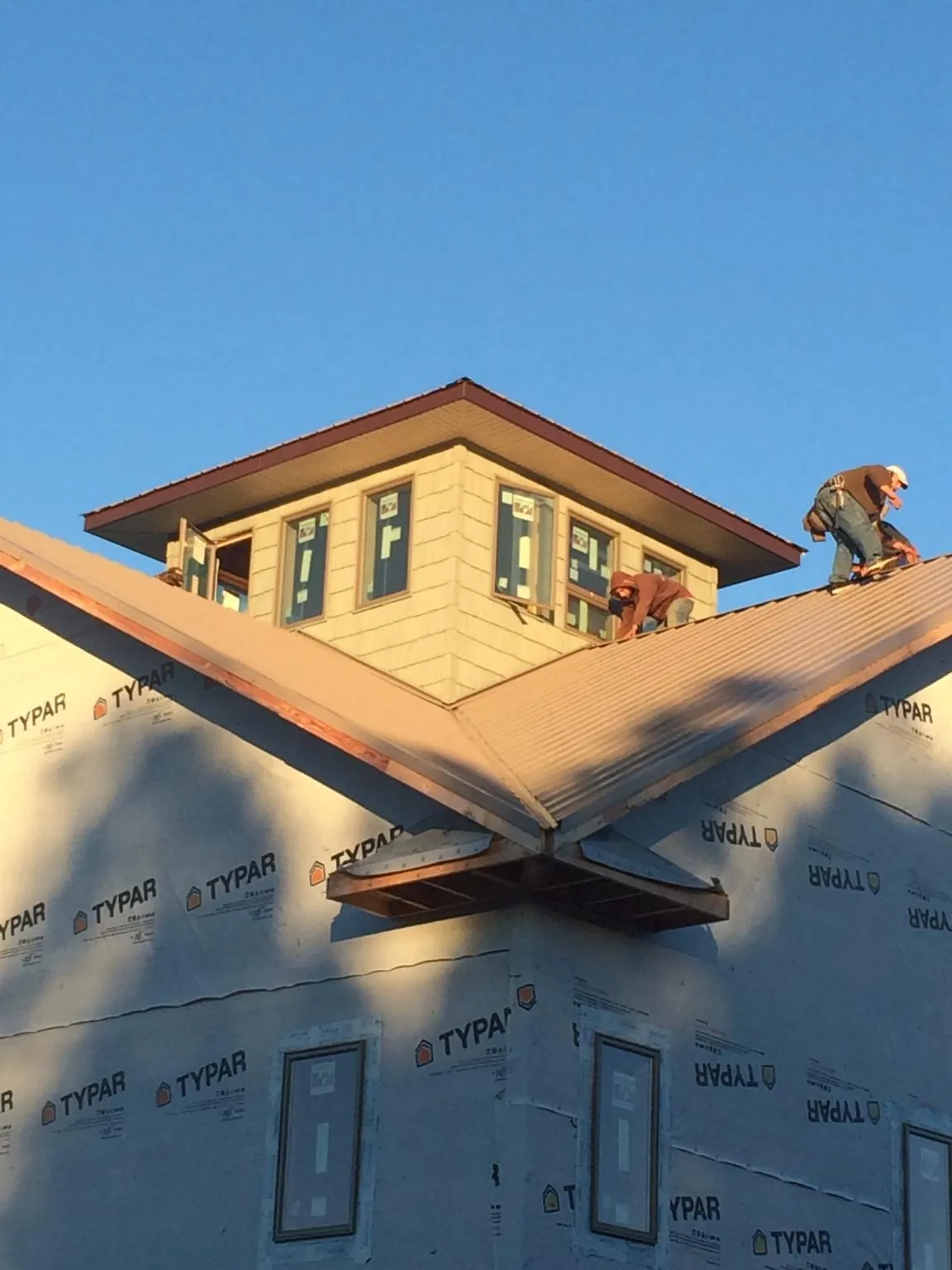Roofers working around a rooftop cupola on a new metal roof at sunset — Roof Waterproofing in Johns Island by Roofing Brothers